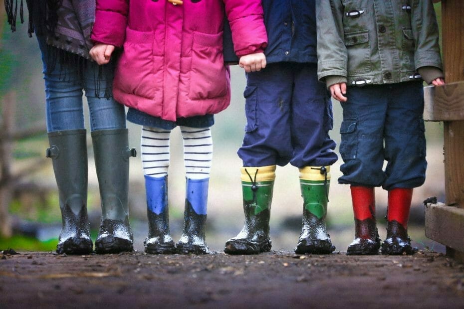 Child Benefit Cancellation: Four children standing hand in hand with rubber boots in the mud